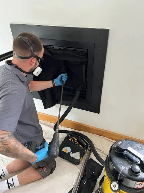 Chimney technician inspecting a modern black fireplace opening