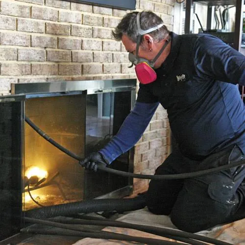 Chimney professional wearing respiratory protection while cleaning a fireplace